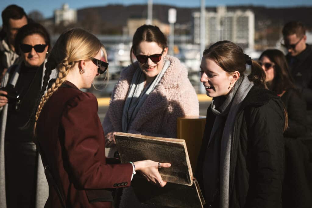 A woman with an antique looking book, storytelling to two female tourists 